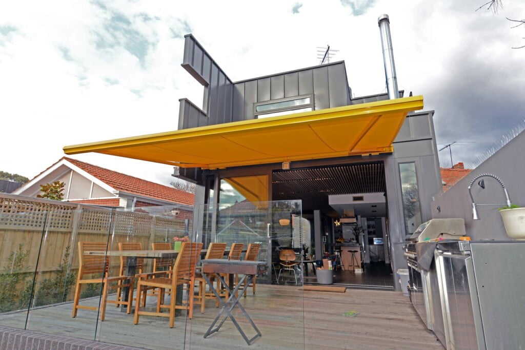 Photo of deck at rear of house with yellow awning.
